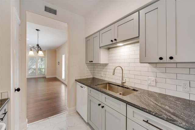 kitchen with backsplash, sink, white dishwasher, and dark stone countertops