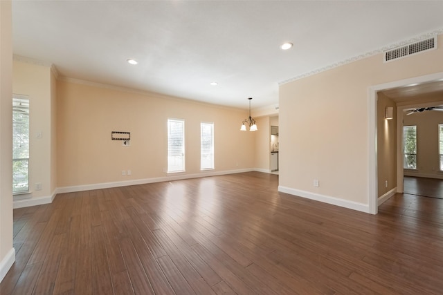 unfurnished room with dark wood-type flooring, ornamental molding, and a notable chandelier