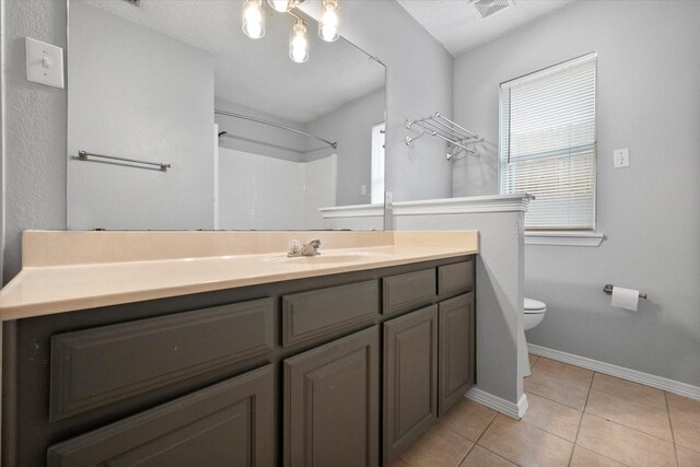 bathroom featuring tile patterned flooring, a healthy amount of sunlight, vanity, and toilet