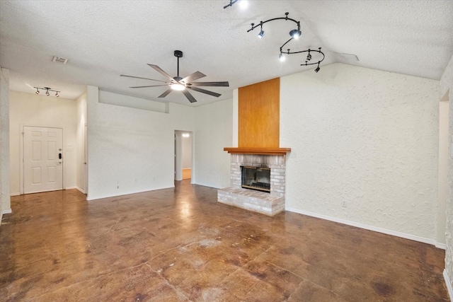 unfurnished living room with lofted ceiling, a brick fireplace, a textured ceiling, and ceiling fan