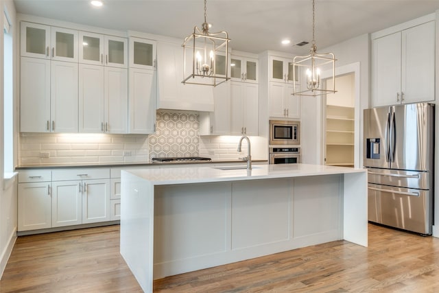 kitchen featuring stainless steel appliances, sink, white cabinetry, and a kitchen island with sink