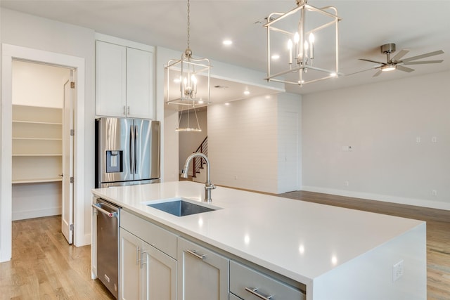 kitchen with a center island with sink, sink, white cabinetry, light wood-type flooring, and stainless steel appliances