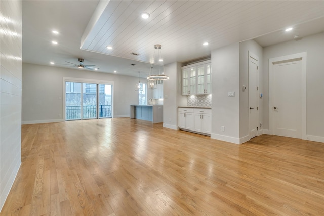 unfurnished living room with light hardwood / wood-style floors, sink, wood ceiling, and ceiling fan with notable chandelier