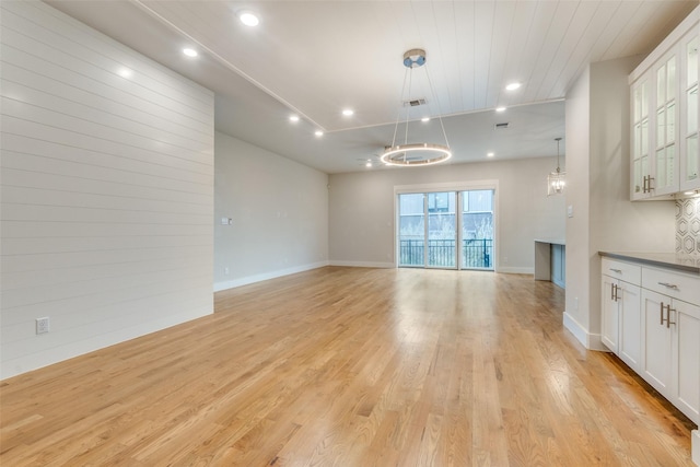 unfurnished living room featuring an inviting chandelier, wood ceiling, and light wood-type flooring