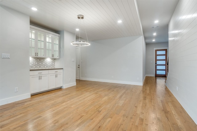 unfurnished dining area with light wood-type flooring and wood ceiling