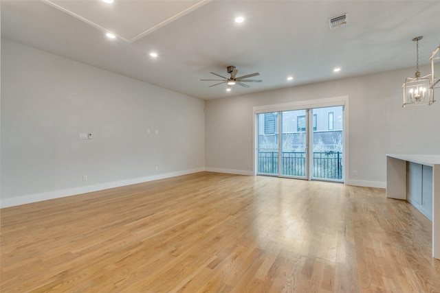 unfurnished living room with ceiling fan with notable chandelier and light hardwood / wood-style floors