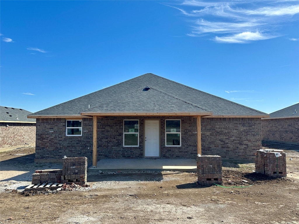 rear view of house with a patio, brick siding, a shingled roof, and cooling unit