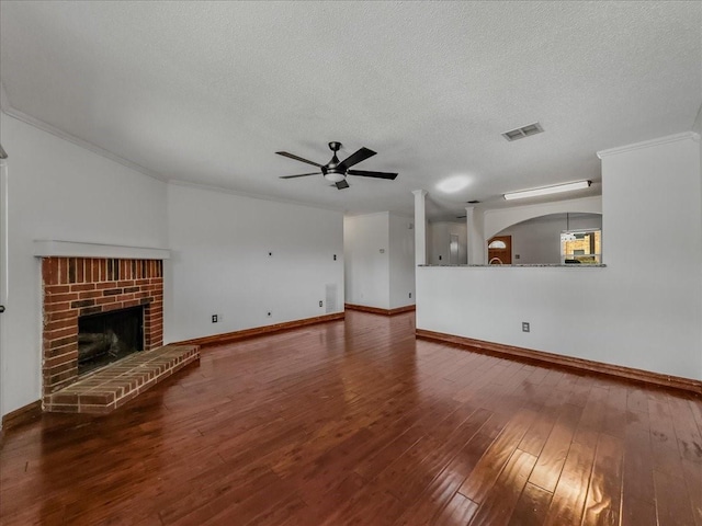 unfurnished living room with crown molding, a fireplace, a textured ceiling, dark hardwood / wood-style flooring, and ceiling fan