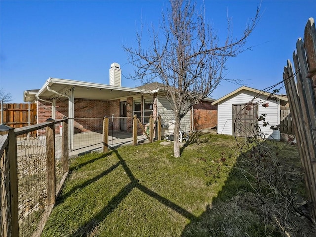 rear view of property featuring a patio area, a lawn, and a storage unit