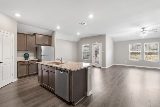 kitchen with lofted ceiling, refrigerator, a center island with sink, stainless steel dishwasher, and sink