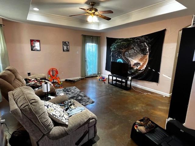 living room featuring ceiling fan, a tray ceiling, and ornamental molding