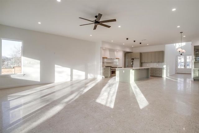 unfurnished living room featuring a healthy amount of sunlight, sink, and ceiling fan