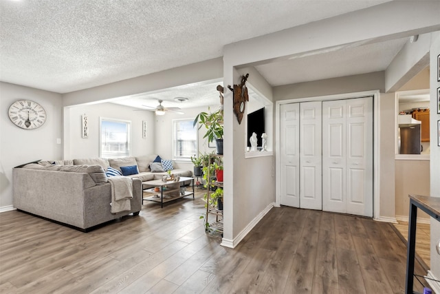 living room with ceiling fan, wood-type flooring, and a textured ceiling