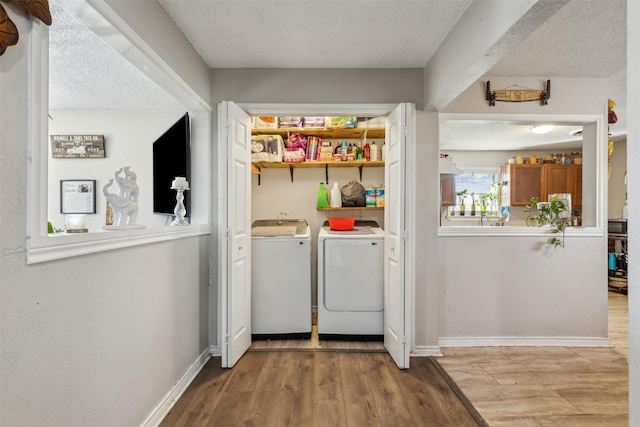 clothes washing area featuring a textured ceiling, light hardwood / wood-style flooring, and washing machine and clothes dryer