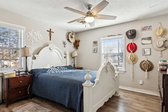 bedroom featuring ceiling fan, dark hardwood / wood-style floors, multiple windows, and a textured ceiling