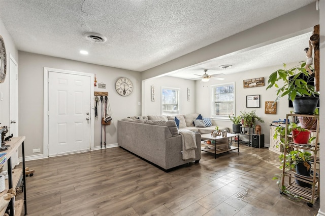 living room featuring ceiling fan, a textured ceiling, and dark hardwood / wood-style flooring