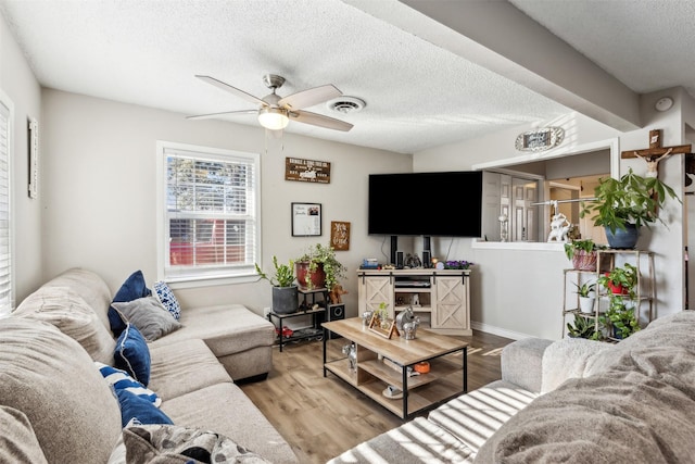 living room featuring hardwood / wood-style flooring, a textured ceiling, and ceiling fan