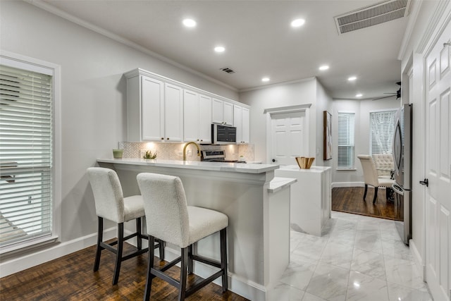 7800 Glenoaks Dr, Frisco, TX 75034 - kitchen featuring white cabinets, stainless steel appliances, tasteful backsplash, kitchen peninsula, and a breakfast bar