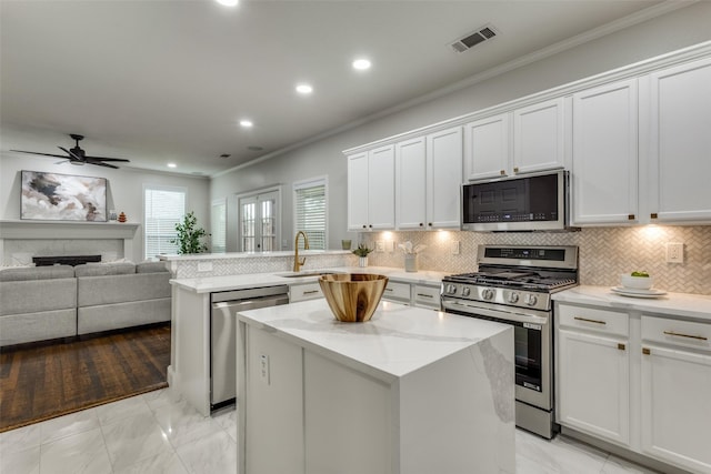 7800 Glenoaks Dr, Frisco, TX 75034 - kitchen with backsplash, a kitchen island, sink, white cabinetry, and stainless steel appliances