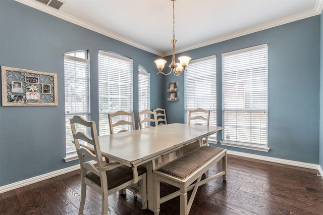 dining space featuring dark hardwood / wood-style flooring, ornamental molding, and an inviting chandelier