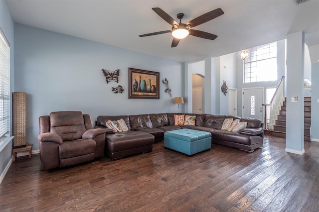 living area featuring ceiling fan, arched walkways, stairs, visible vents, and dark wood-style floors
