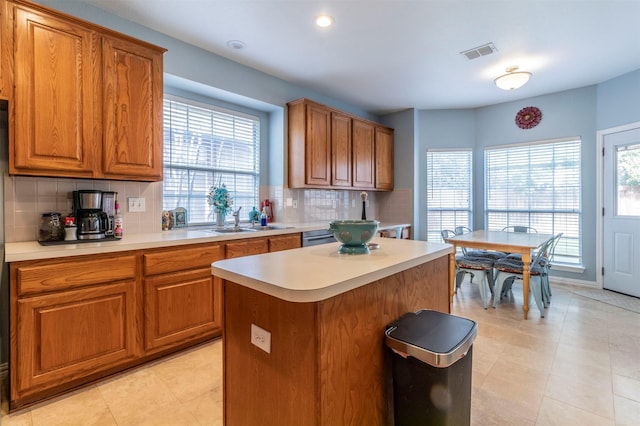 kitchen featuring a healthy amount of sunlight, backsplash, sink, and a kitchen island