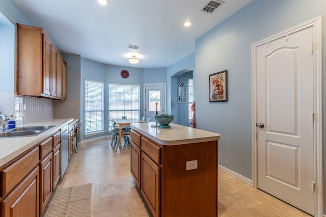 kitchen with a kitchen island, stainless steel dishwasher, tasteful backsplash, and sink