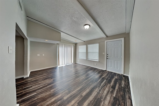 interior space with a textured ceiling, dark hardwood / wood-style flooring, and lofted ceiling with beams