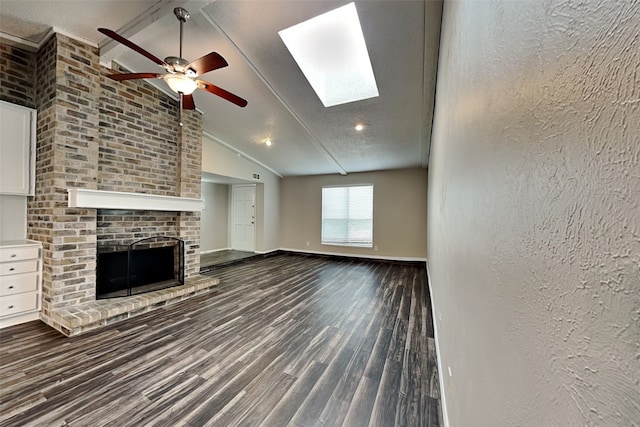 unfurnished living room featuring vaulted ceiling with skylight, a textured ceiling, hardwood / wood-style floors, a fireplace, and ceiling fan