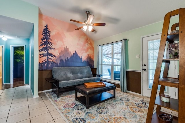 living area with lofted ceiling, wainscoting, light tile patterned flooring, and a ceiling fan