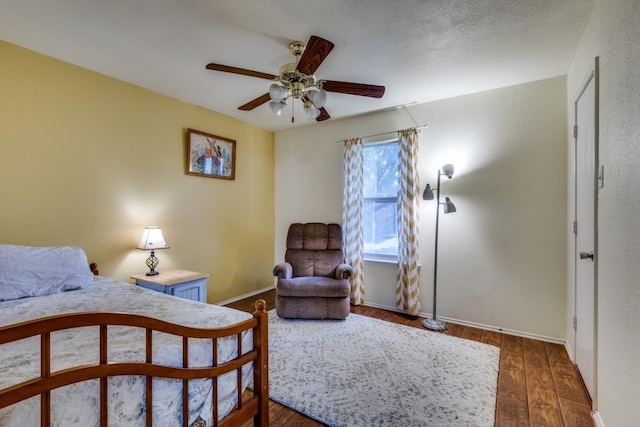 bedroom featuring dark wood-style floors, a textured ceiling, baseboards, and a ceiling fan