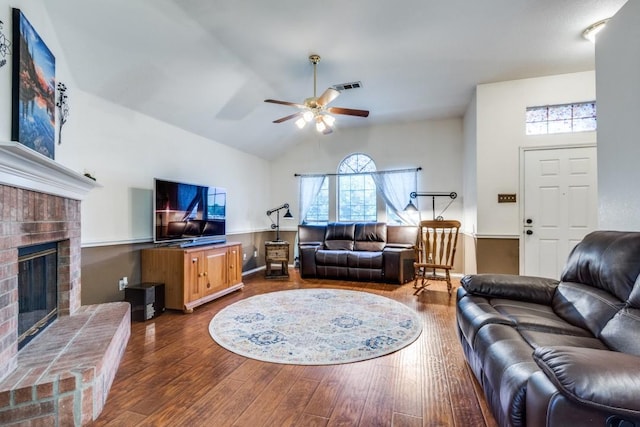 living area featuring ceiling fan, a fireplace, wood finished floors, visible vents, and vaulted ceiling