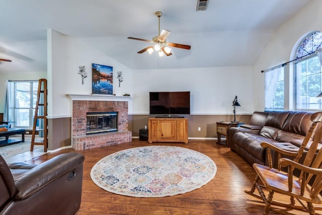 living area featuring visible vents, a ceiling fan, lofted ceiling, wood finished floors, and a brick fireplace