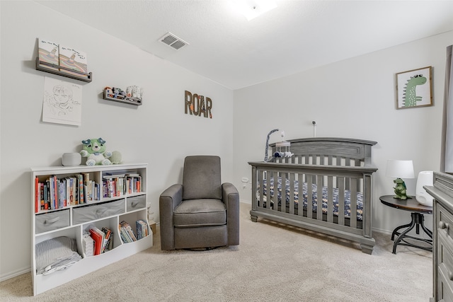 bedroom featuring light carpet, a textured ceiling, and a nursery area