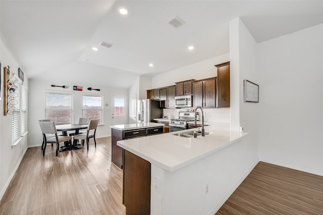 kitchen featuring appliances with stainless steel finishes, lofted ceiling, sink, backsplash, and kitchen peninsula