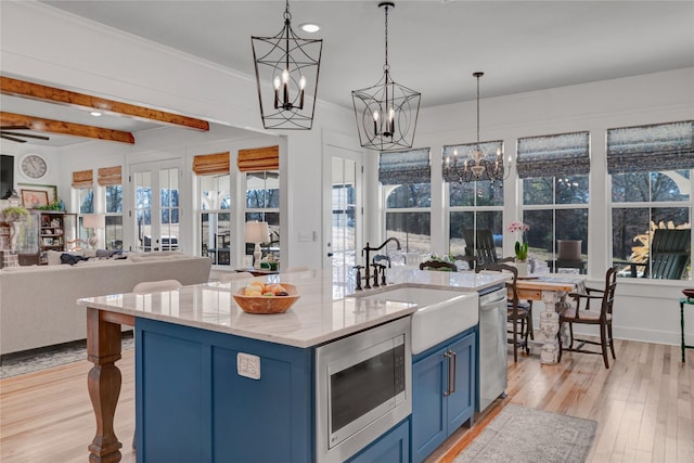 kitchen featuring stainless steel appliances, sink, blue cabinets, and decorative light fixtures