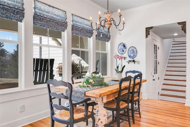 dining space featuring an inviting chandelier, a wealth of natural light, crown molding, and wood-type flooring