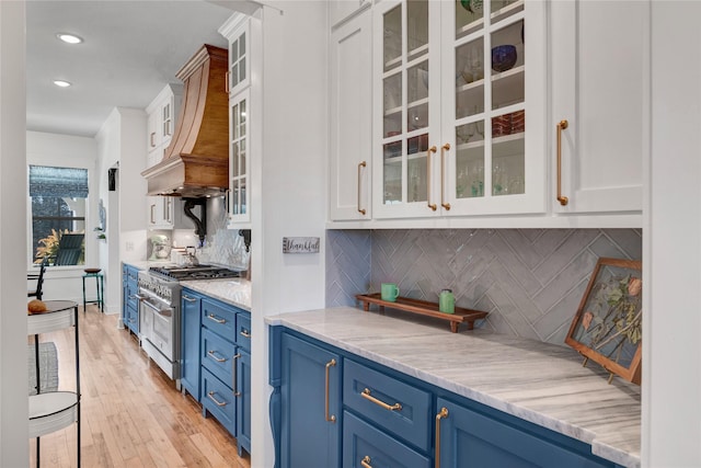 kitchen featuring white cabinets, light stone countertops, blue cabinets, and high end stainless steel range oven