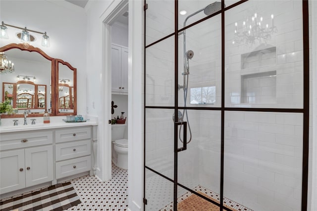 bathroom with vanity, an inviting chandelier, toilet, ornamental molding, and tiled shower