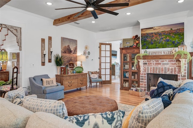 living room featuring a brick fireplace, wood-type flooring, beamed ceiling, ornamental molding, and french doors