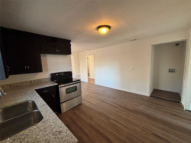 kitchen with electric stove, sink, light stone countertops, dark wood-type flooring, and a textured ceiling