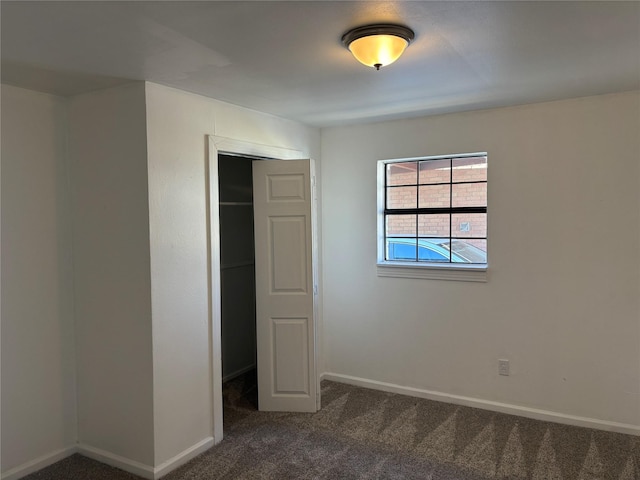 unfurnished bedroom with dark carpet and a closet