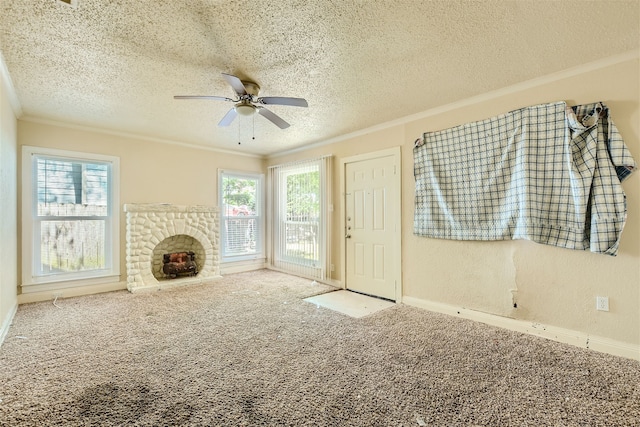 unfurnished living room featuring carpet, ceiling fan, a fireplace, crown molding, and a textured ceiling