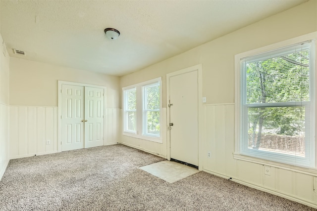 doorway to outside featuring a textured ceiling and light carpet