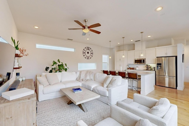 living room featuring ceiling fan and light hardwood / wood-style flooring