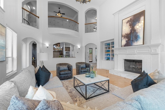 living area featuring a ceiling fan, built in features, and a tiled fireplace