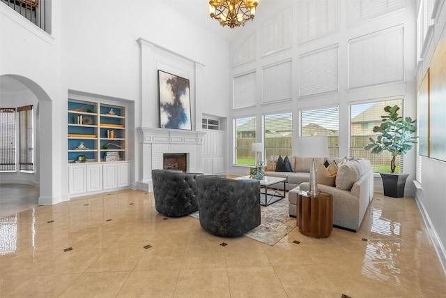 living area with arched walkways, a high ceiling, a brick fireplace, and an inviting chandelier