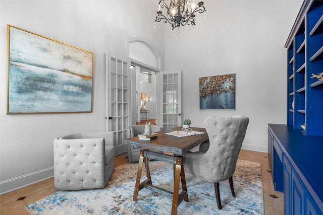 office space featuring tile patterned floors, a notable chandelier, a high ceiling, and baseboards