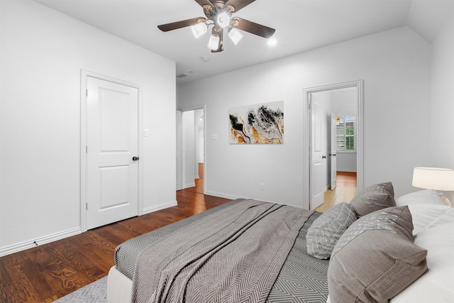 bedroom with a ceiling fan, vaulted ceiling, wood finished floors, and baseboards