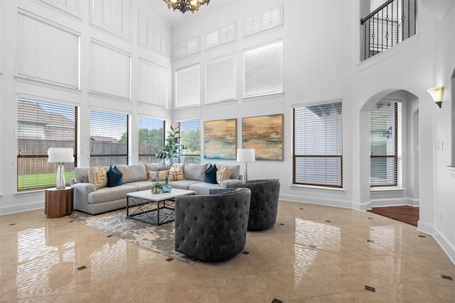 living area featuring marble finish floor, a high ceiling, baseboards, and an inviting chandelier